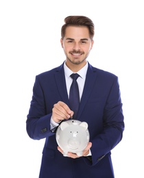 Young businessman putting money into piggy bank on white background