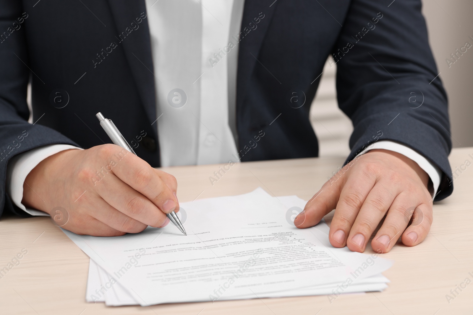 Photo of Man signing document at wooden table, closeup