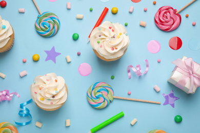 Photo of Flat lay composition with cupcakes on light blue background. Birthday party