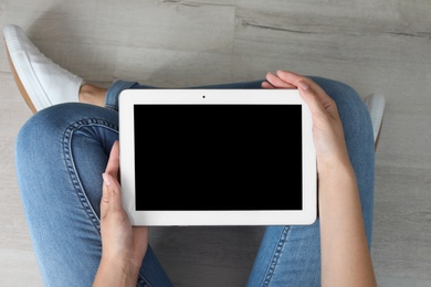 Woman holding tablet with blank screen indoors. Mockup for design