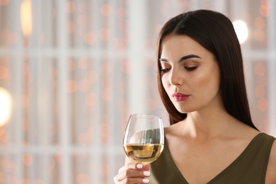 Photo of Beautiful young woman with glass of luxury white wine indoors. Space for text