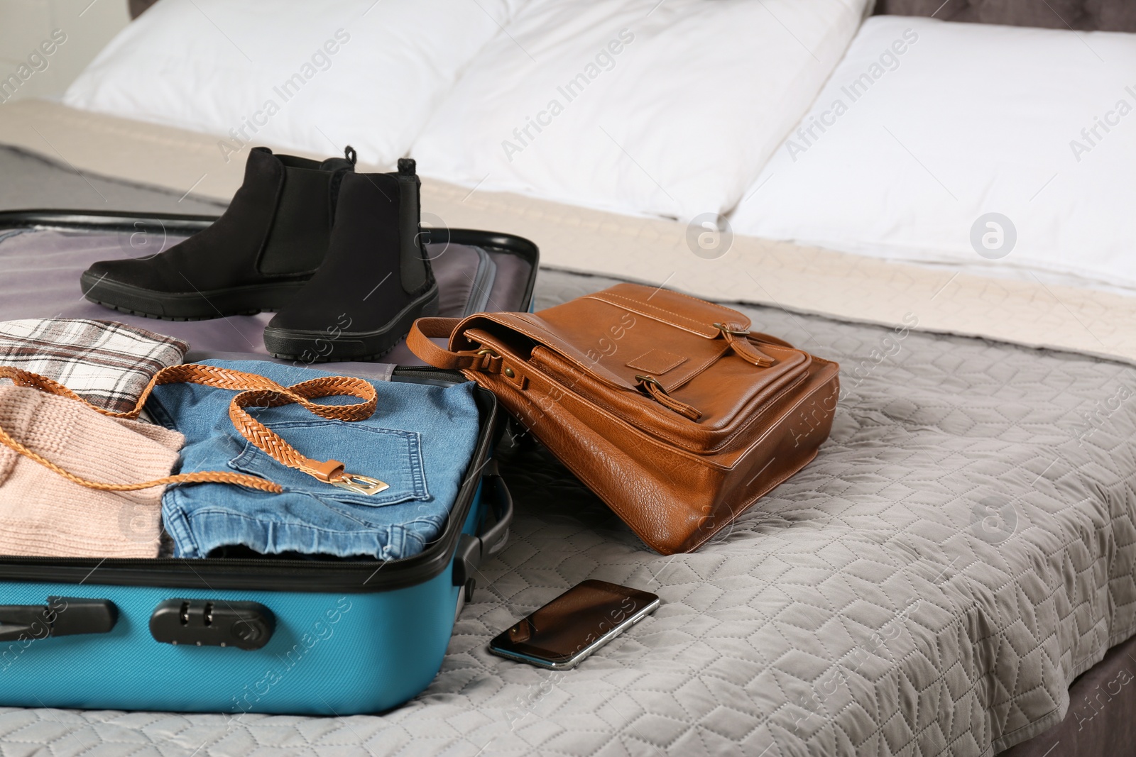 Photo of Suitcase packed for trip on bed in room