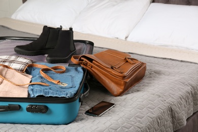 Photo of Suitcase packed for trip on bed in room