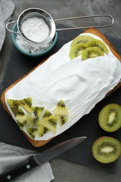 Delicious homemade yogurt cake with kiwi and cream on gray table, flat lay