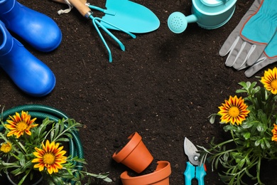 Photo of Flat lay composition with gardening equipment and flowers on soil, space for text