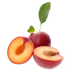 Whole and cut ripe plums with green leaves isolated on white