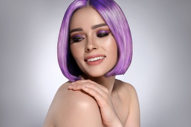 Image of Hair styling. Attractive woman with bright violet hair on grey background