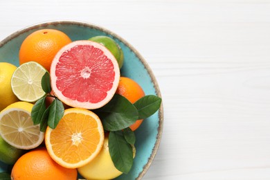 Different cut and whole citrus fruits on white wooden table, top view. Space for text