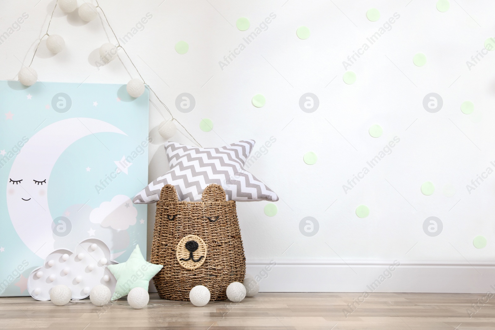 Photo of Picture, lamp and wicker basket on floor indoors, space for text. Children's room interior