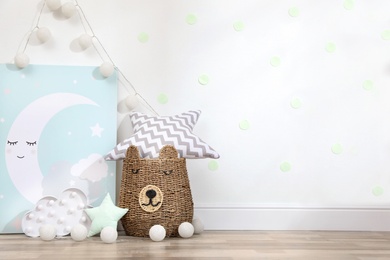 Picture, lamp and wicker basket on floor indoors, space for text. Children's room interior