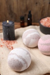 Bath bombs, sea salt, and burning candle on table, closeup