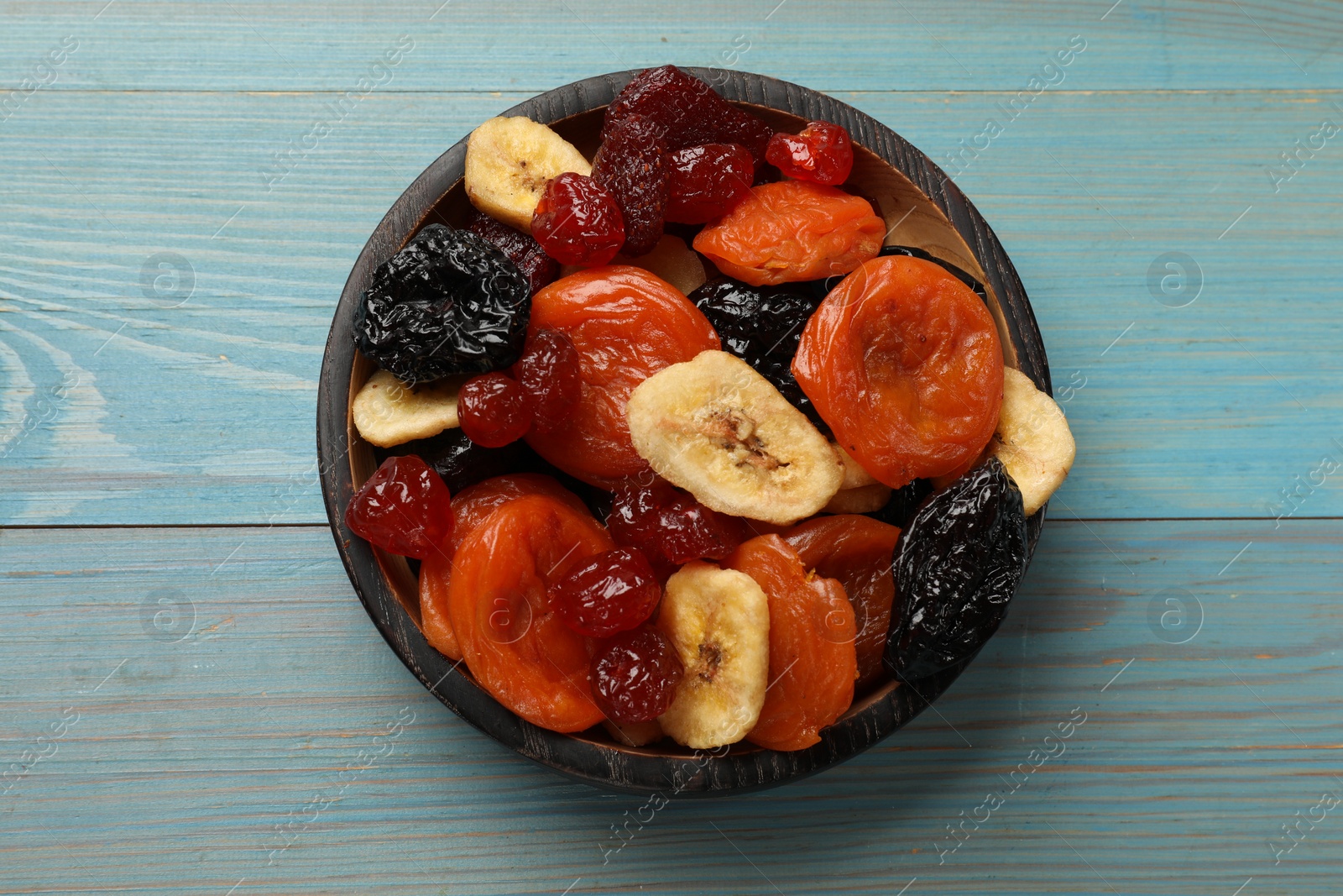 Photo of Mix of delicious dried fruits on light blue wooden table