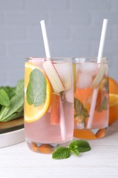 Photo of Tasty rhubarb cocktail with orange on white wooden table, closeup