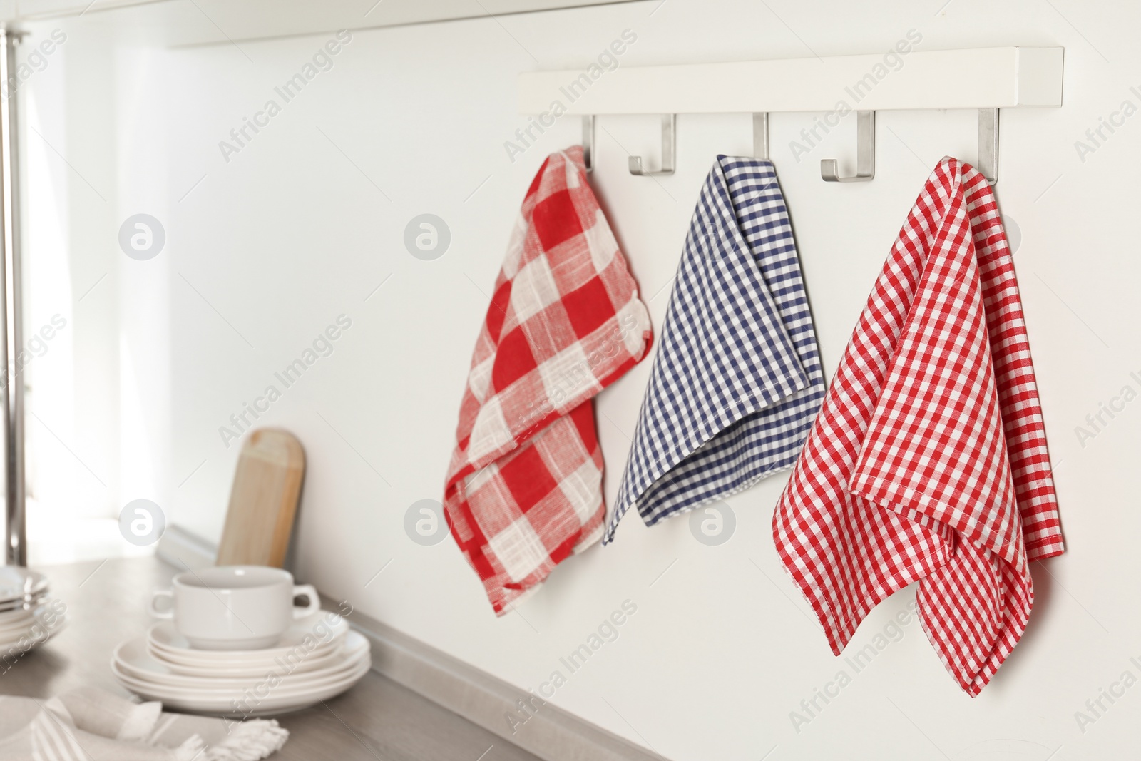 Photo of Different kitchen towels hanging on hook rack indoors