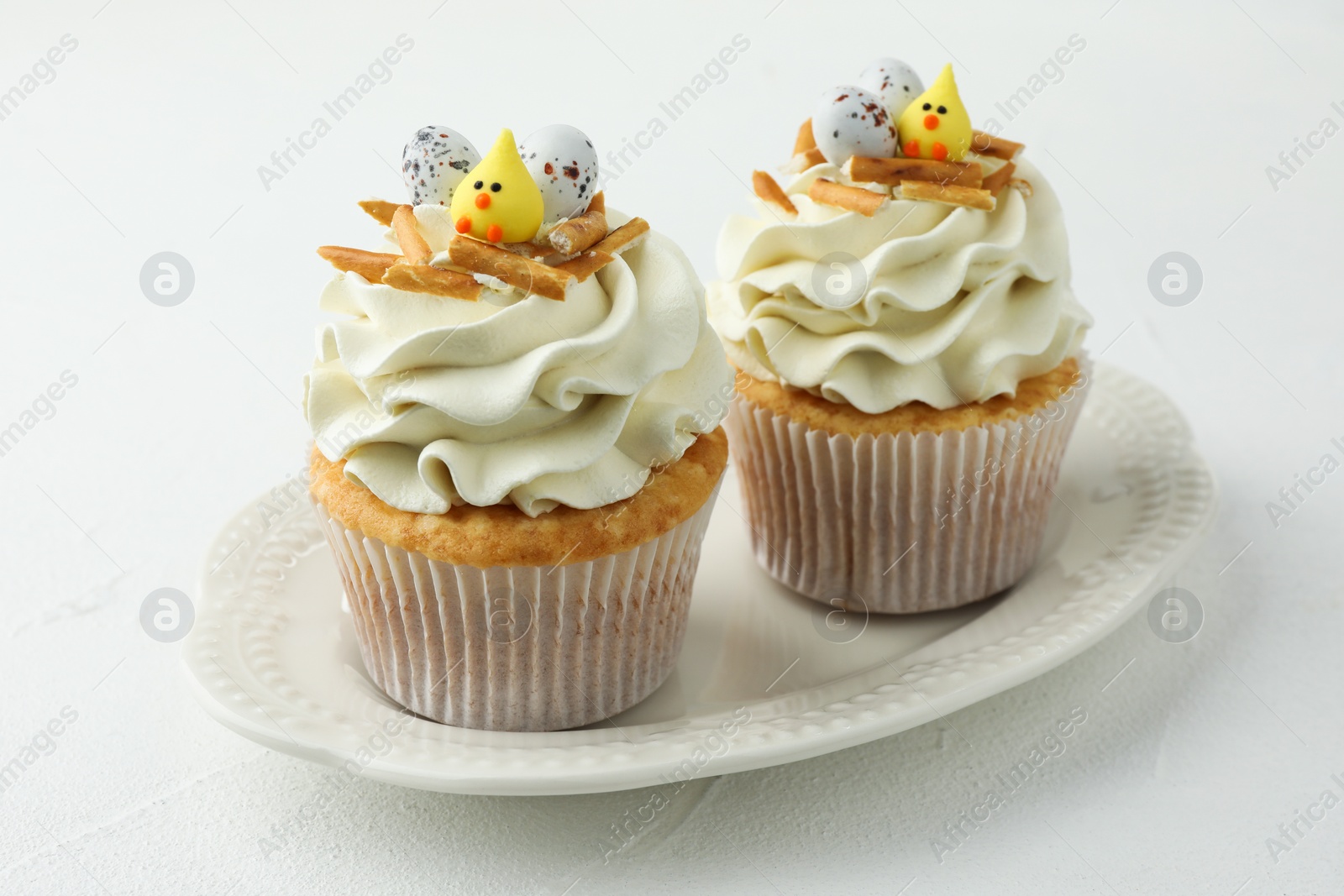 Photo of Tasty Easter cupcakes with vanilla cream on white table