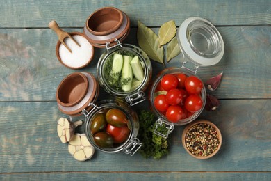 Photo of Pickling jars with fresh ripe vegetables and spices on blue wooden table, flat lay