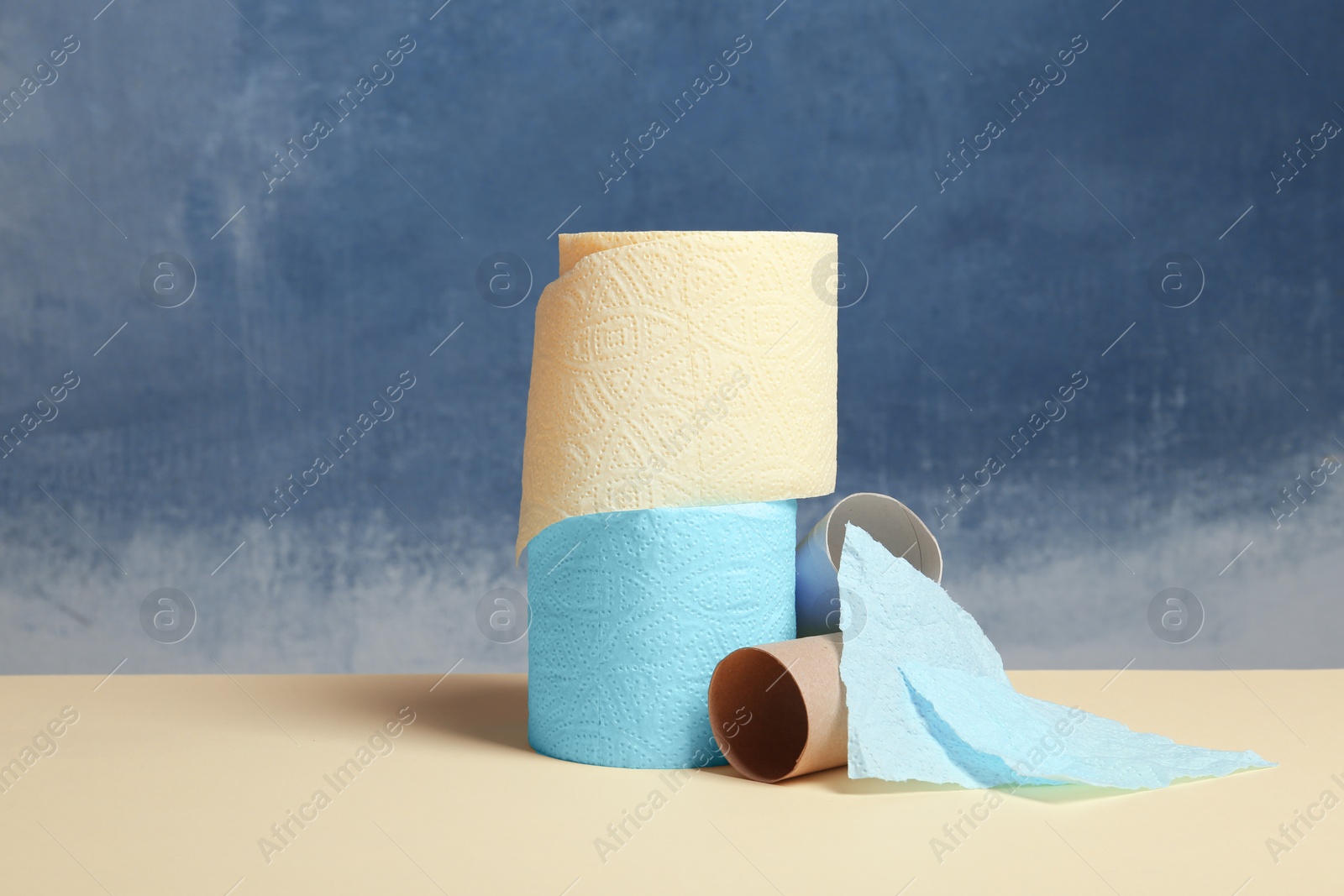 Photo of Full and empty toilet paper rolls on table against color background