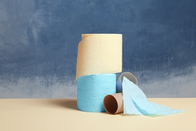 Photo of Full and empty toilet paper rolls on table against color background