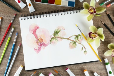 Flat lay composition with beautiful drawing of orchid
flowers on wooden table