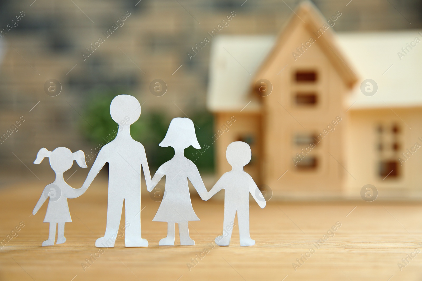 Photo of Composition with paper family cutout and house model on table