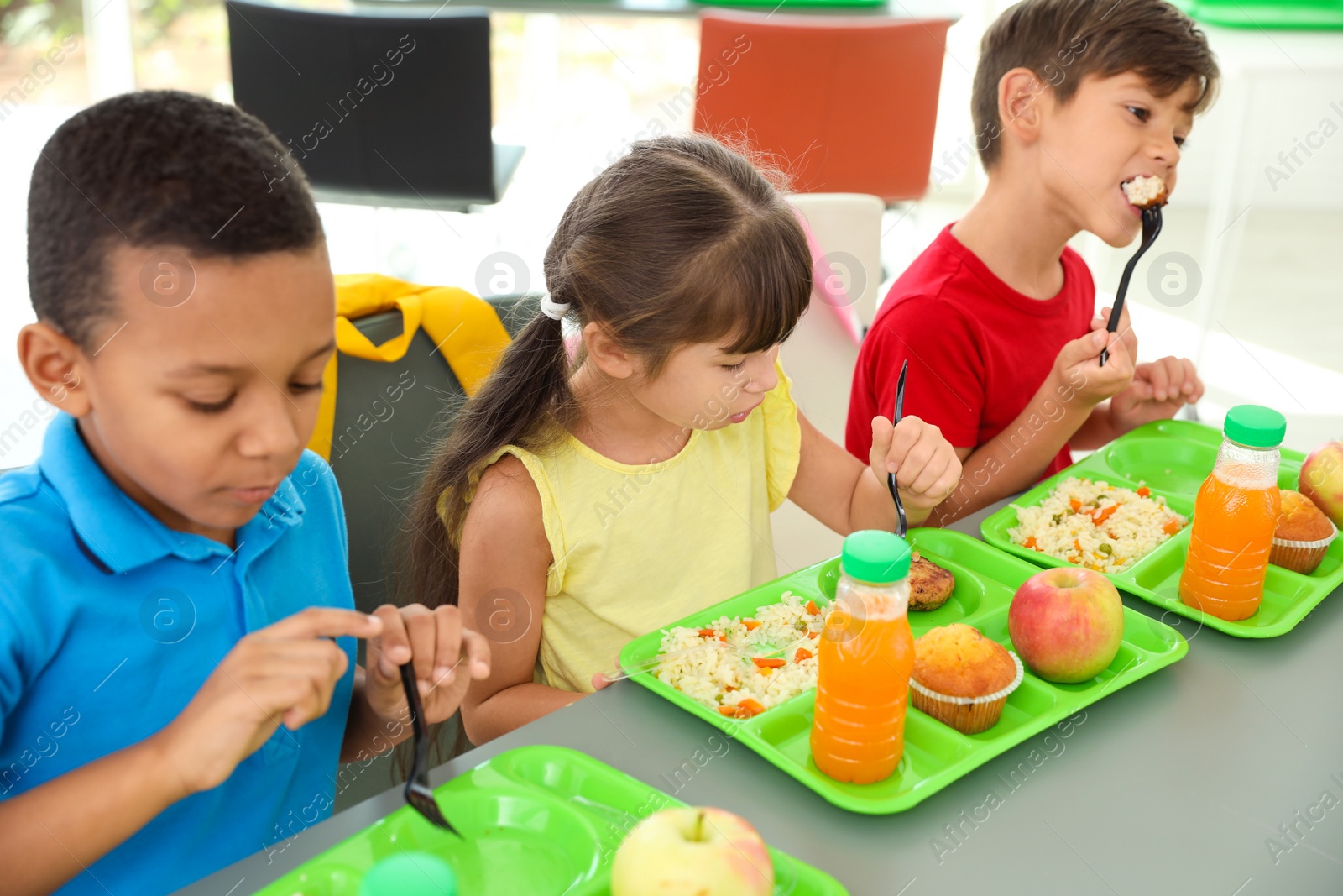 Photo of Children sitting at table and eating healthy food during break at school