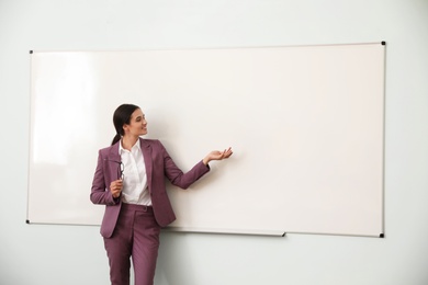 Photo of Female teacher near whiteboard in modern classroom