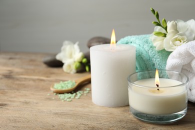 Beautiful composition with burning candles and different spa products on wooden table. Space for text