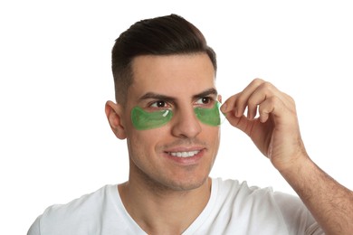 Photo of Man applying green under eye patch on white background
