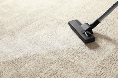 Photo of Removing dirt from light carpet with vacuum cleaner. Space for text