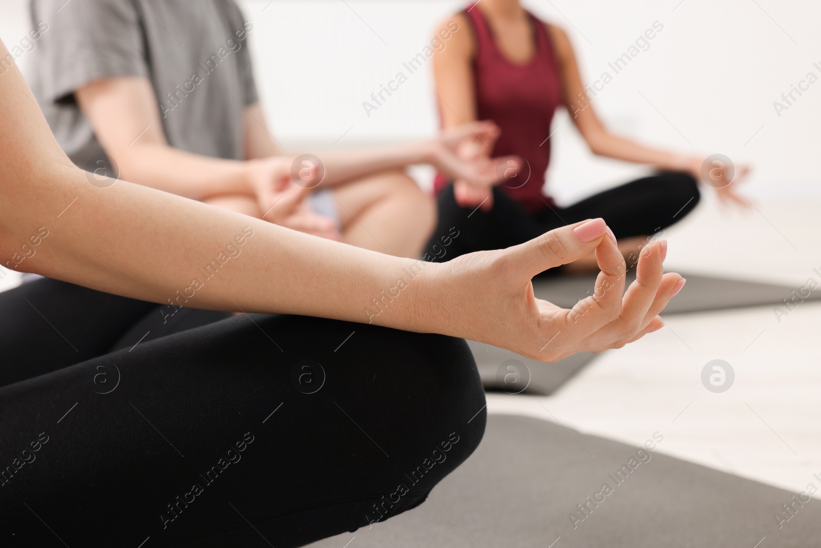 Photo of Group of people practicing yoga on mats indoors, closeup