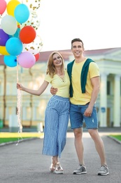 Photo of Young couple with colorful balloons outdoors on sunny day