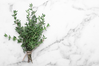 Photo of Bunch of aromatic fresh thyme on white marble table, top view. Space for text