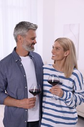 Happy affectionate couple with glasses of wine at home. Romantic date