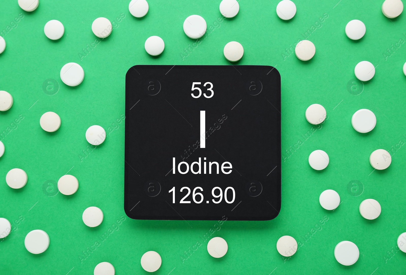 Photo of Card with iodine element and pills on green background, flat lay