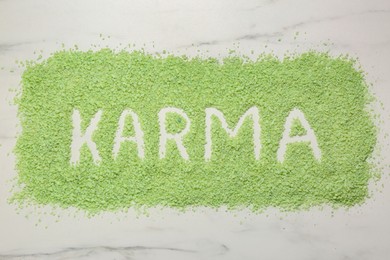 Photo of Word Karma made of sea salt on white marble table, top view