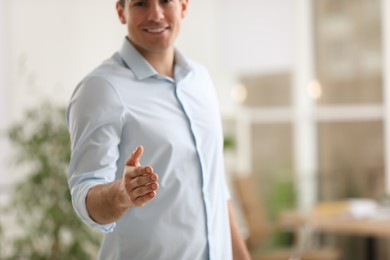 Photo of Businessman offering handshake in office, closeup. Space for text