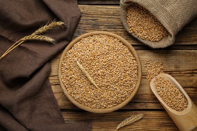 Photo of Ears of wheat and grains on wooden table, flat lay