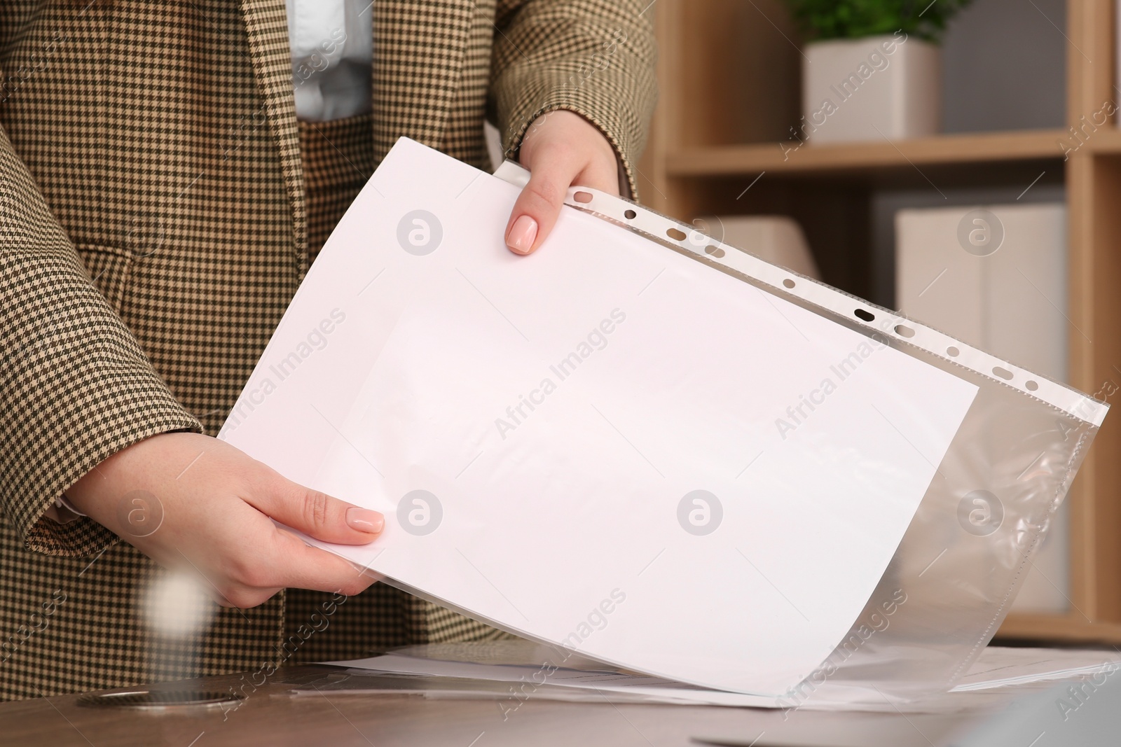 Photo of Businesswoman putting document into punched pocket in office, closeup