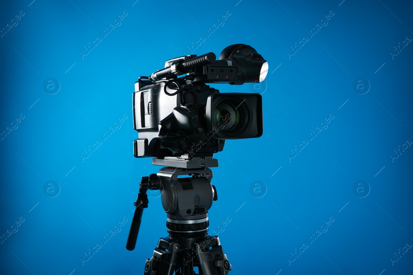 Photo of Modern professional video camera on blue background