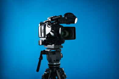 Photo of Modern professional video camera on blue background