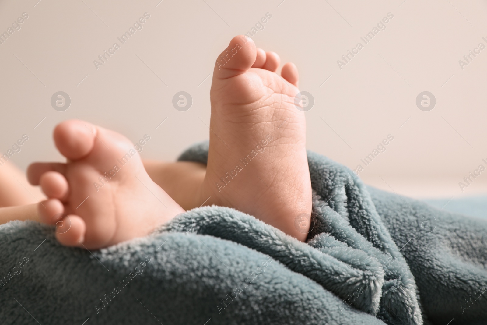 Photo of Little baby lying on soft blanket against light background, closeup. Space for text