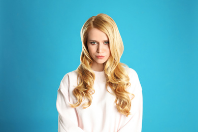 Portrait of beautiful young woman with dyed long hair on blue background