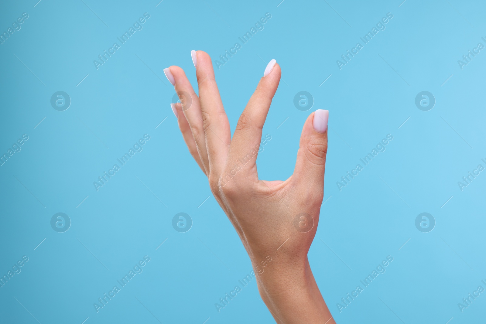 Photo of Woman holding something in hand on light blue background, closeup. Space for text