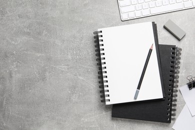 Open blank notebook, keyboard and stationery on light grey table, flat lay. Space for text