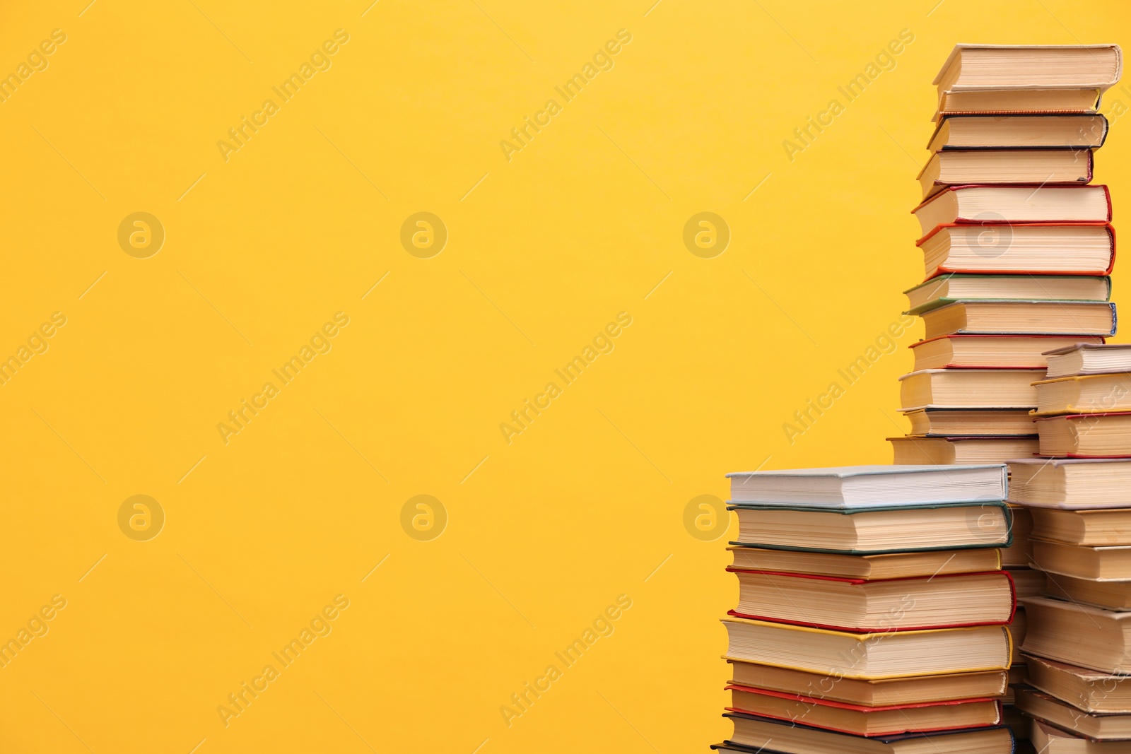 Photo of Many hardcover books on orange background, space for text. Library material