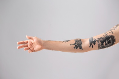 Man's arm with stylish tattoos on grey background