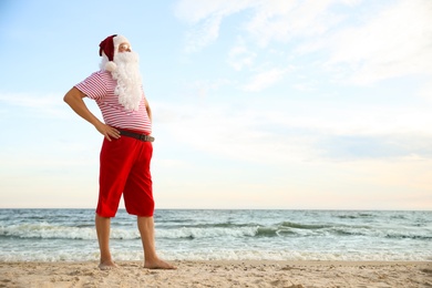 Santa Claus on beach, space for text. Christmas vacation