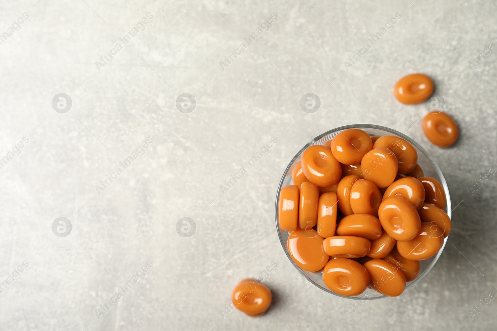 Photo of Dessert bowl filled with tasty candies on light table, top view. Space for text