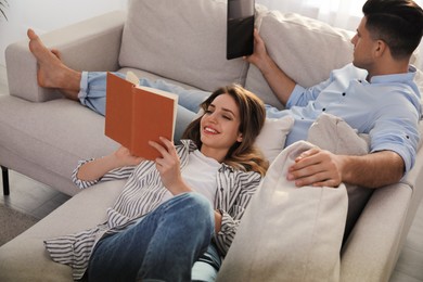 Photo of Happy couple with tablet and book on sofa in living room