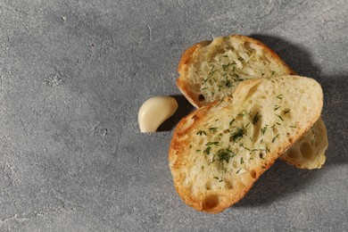 Photo of Tasty baguette with garlic and dill on grey textured table, flat lay. Space for text